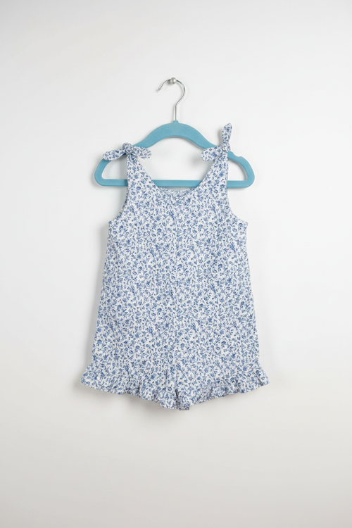 Handmade blue ditsy floral toddler romper with tie straps and ruffle hem on white studio background