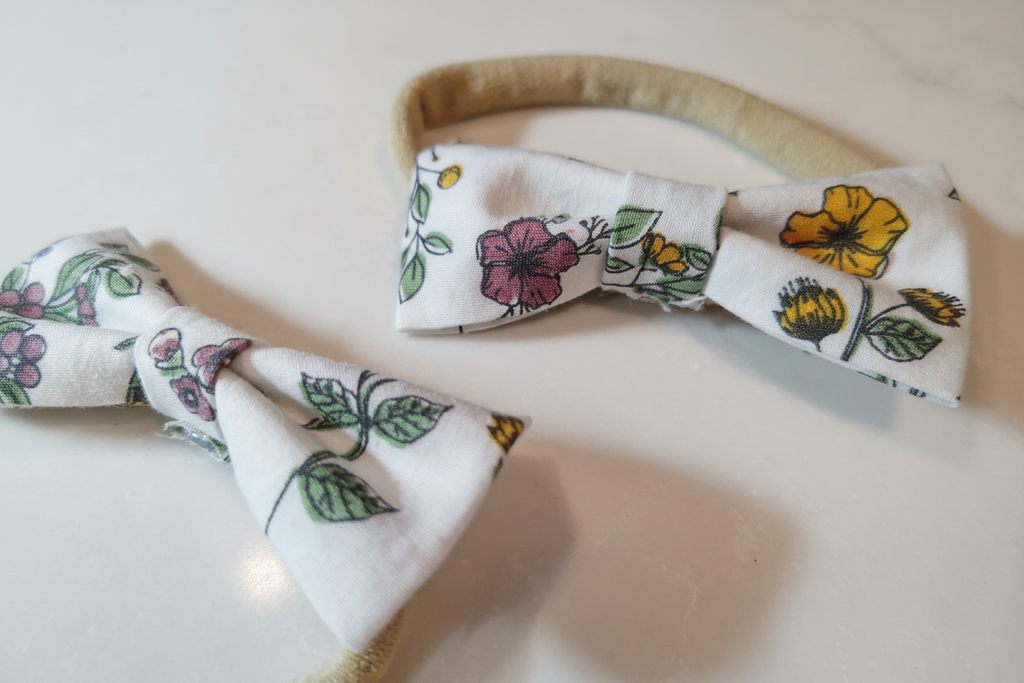 Close-up detail of handmade wildflower print bow baby nylon headbands on white studio background