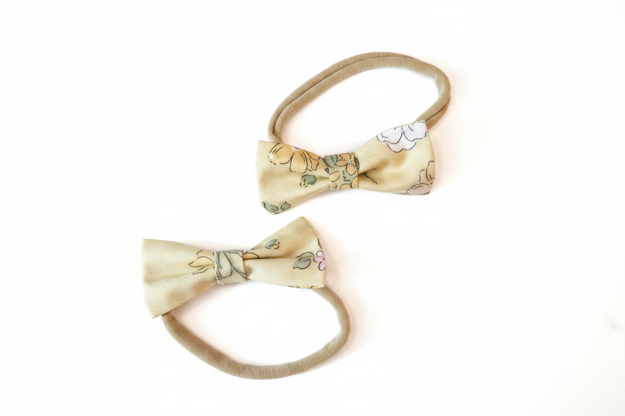 Two sizes of handmade golden floral bow nylon headbands on white studio background