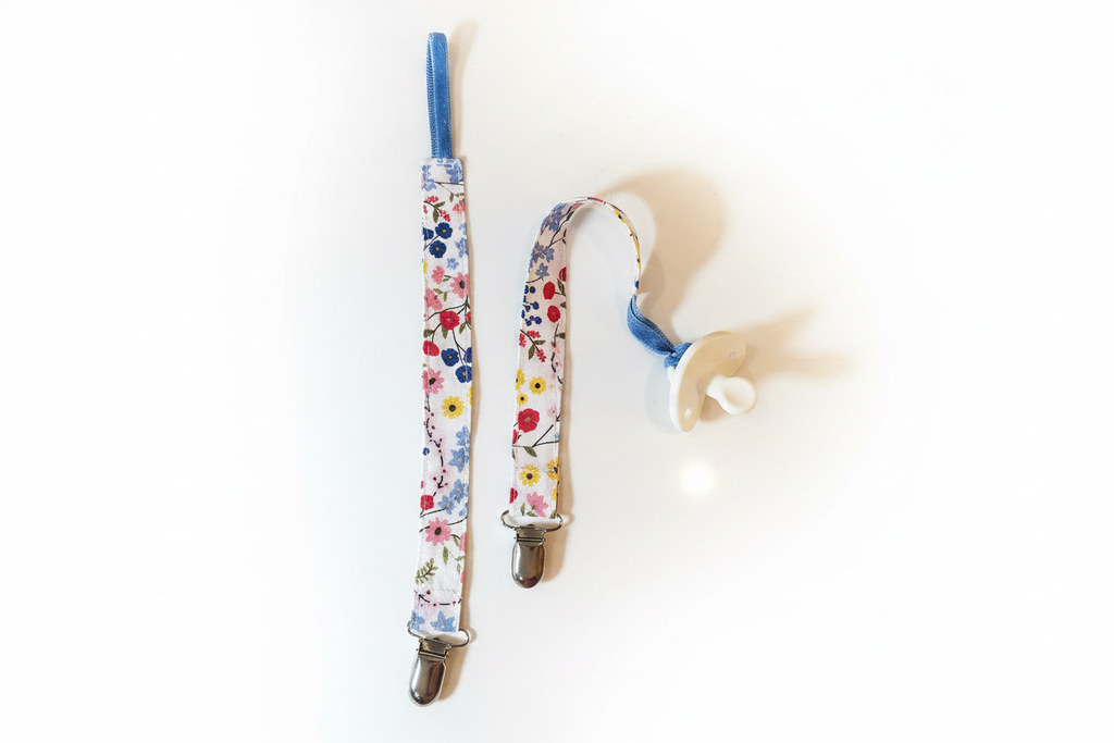 Two handmade wildflower pacifier clips brightened on white studio background