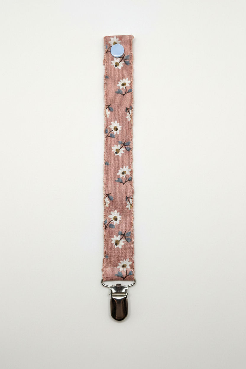 Handmade dusty rose daisy pacifier clip strap with blue snap button and silver metal clip on white studio background