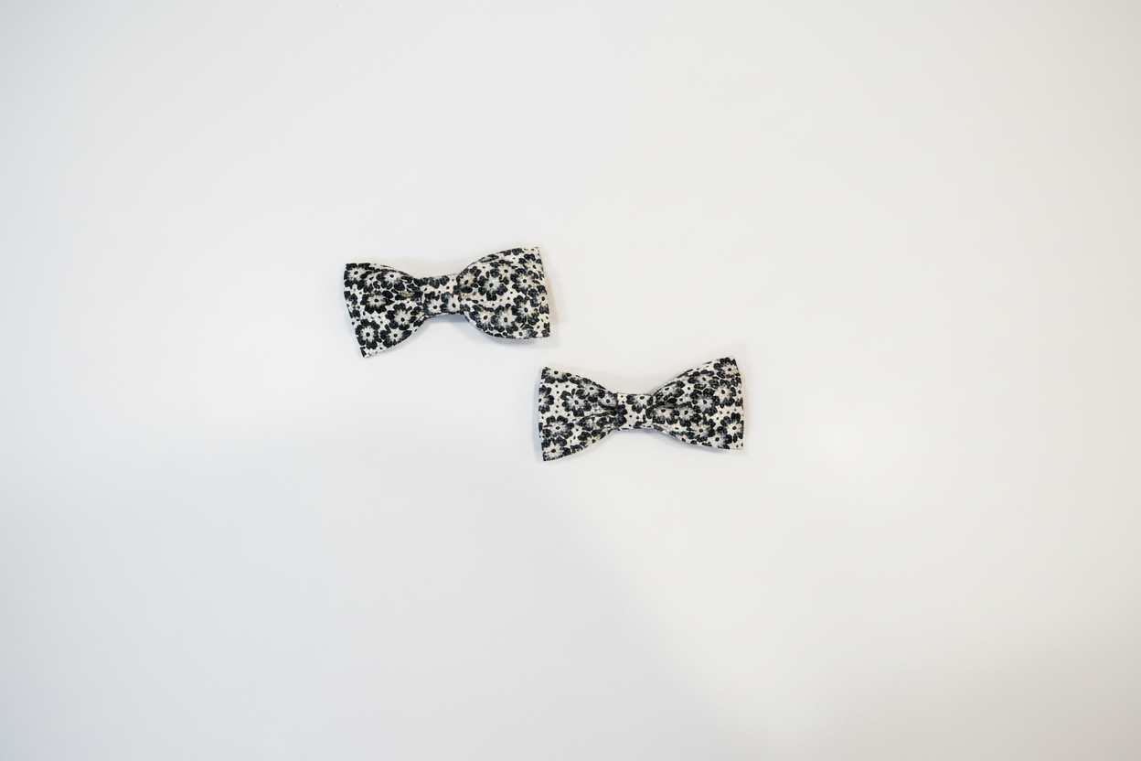 Two sizes of handmade black and white floral daisy baby hair bows on white studio background