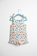 Handmade citrus print toddler romper with tie straps and ruffle hem on white studio background