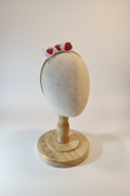 Handmade strawberry bow baby headband on display stand with white studio background
