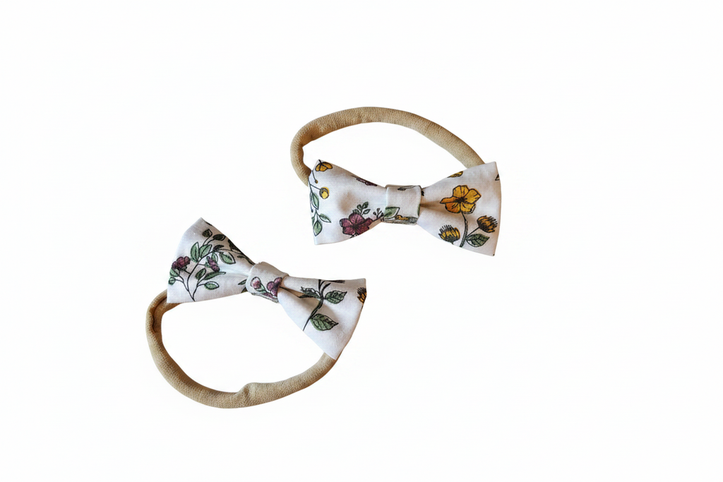 Two sizes of handmade wildflower print bow baby nylon headbands on white studio background