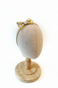 Handmade yellow lemon floral bow baby headband on display stand with white studio background