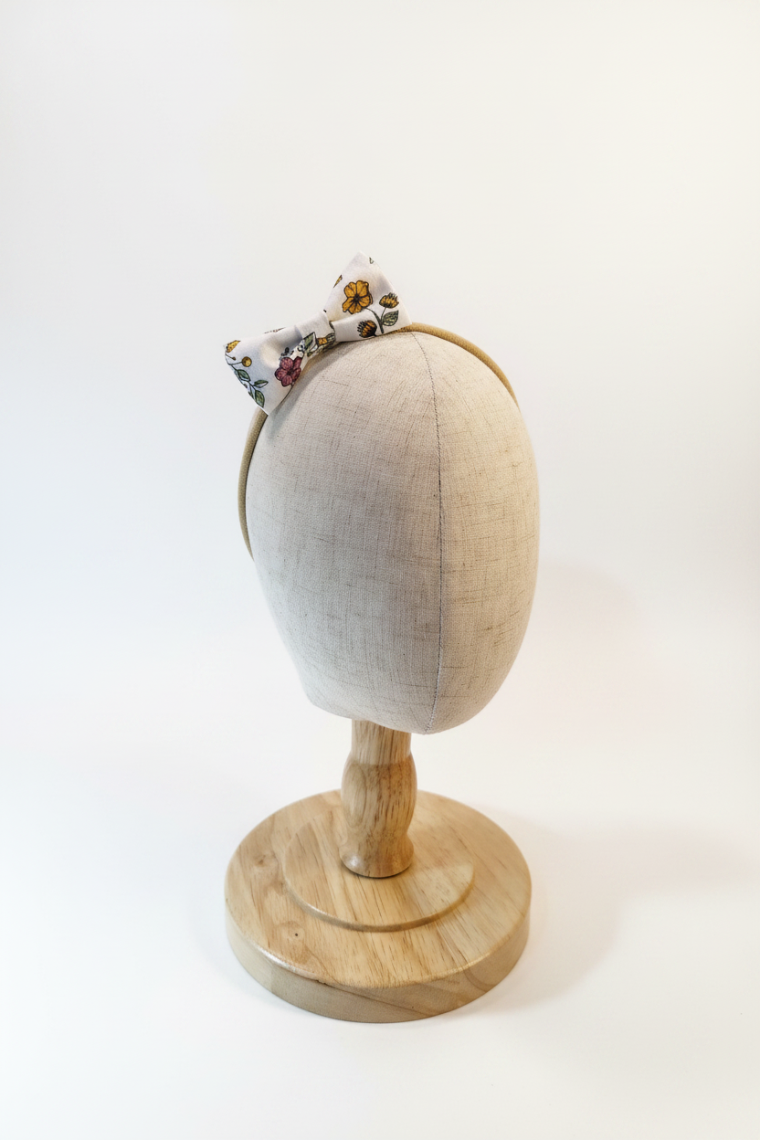 Handmade wildflower print bow baby headband on display stand with white studio background