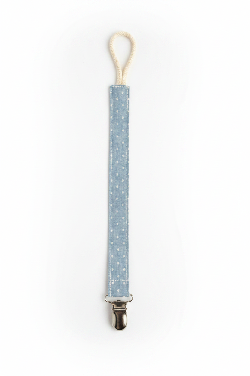 Handmade blue heart pacifier clip flat lay on white studio background