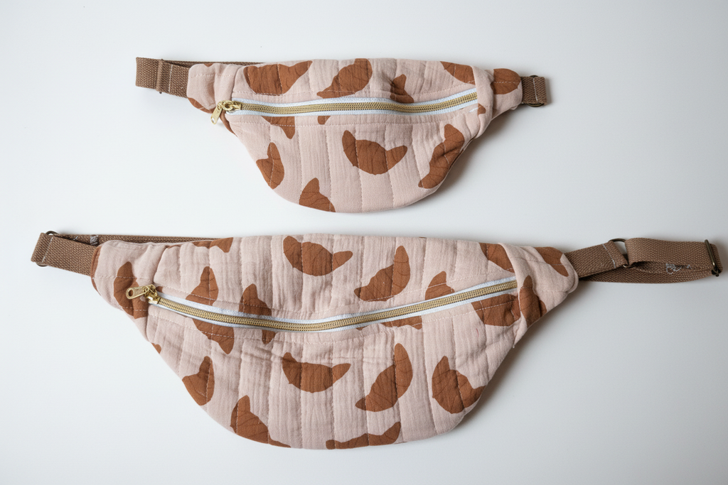 Two closed cow print belt bags - studio background